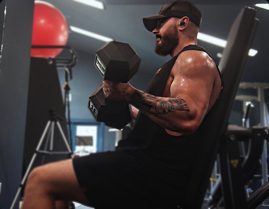 Jot Fuller mid-set, curling a dumbbell in the gym.